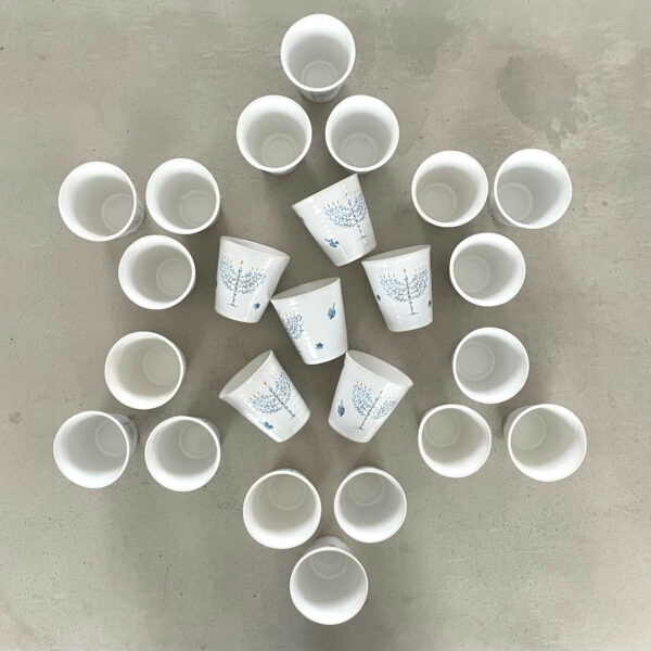 Handgjorda Chanukahmuggar i stengods, arrangerade i Davidsstjärna – blå dekorer med menorah, dreidel och fågelmotiv. En visuell hyllning till högtiden.