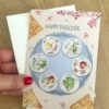 Kort till Pesach med ett illustrerat sederfat med matza bröd runtom och texten "Happy Passover"